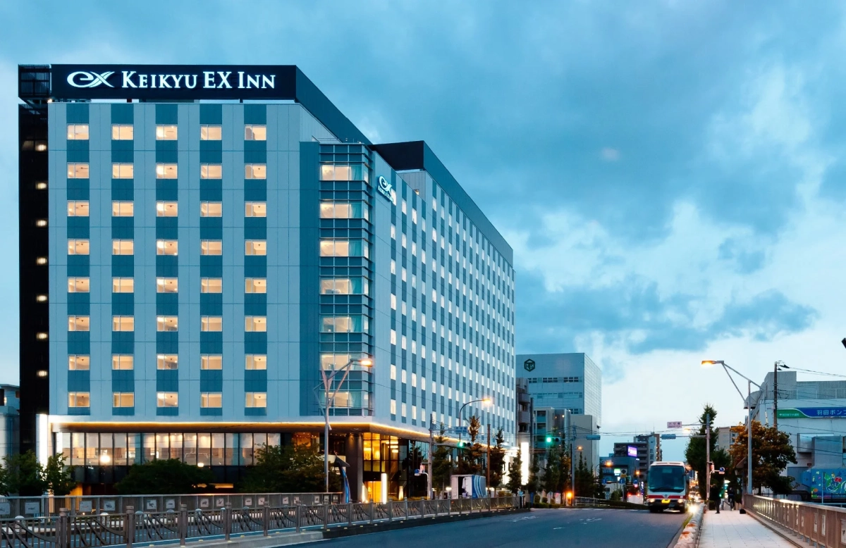 夕暮れ時、街路に面してそびえ立つ「京急EXイン」のホテル