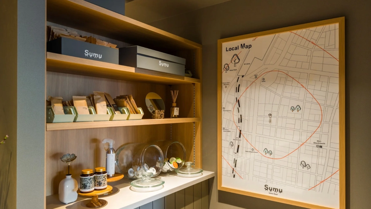木製の棚に様々なアメニティや商品が並べられ、隣には上野周辺の地図が飾られています