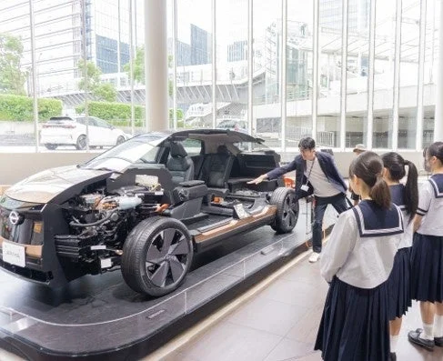 日産ショールームで電気自動車のカットモデルの説明を受ける学生