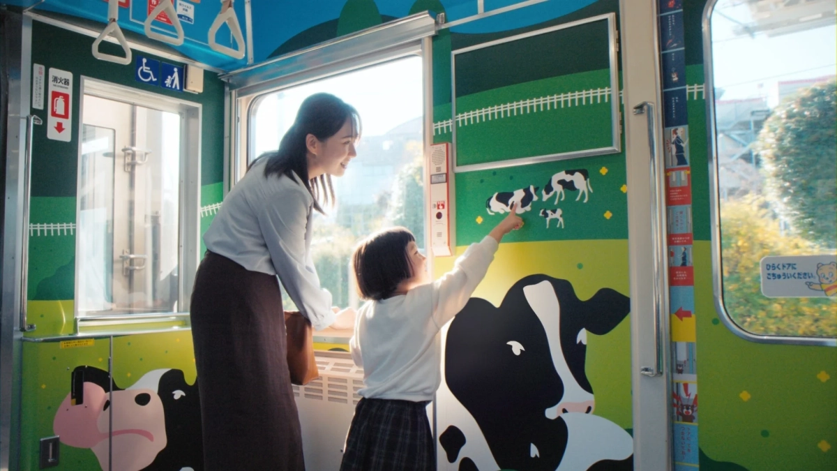 電車内で牛のイラストを見る親子
