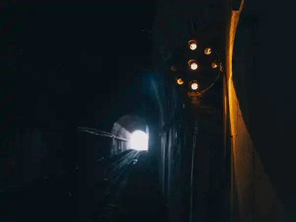 暗い鉄道トンネルの内部から、遠くに見える出口の明るい光を捉えた写真