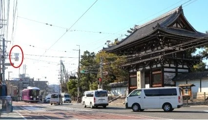 寺院の門、道路、車、路面電車、電線、建物、街並み