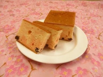 桜柄のピンクの布の上に置かれたピンク色のカステラのようなケーキ