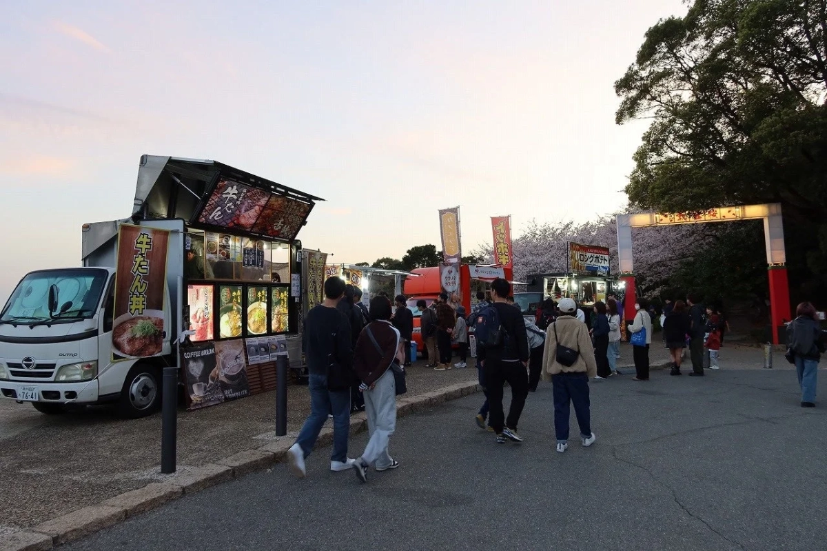 夕暮れ時の桜まつり会場で賑わうフードトラック
