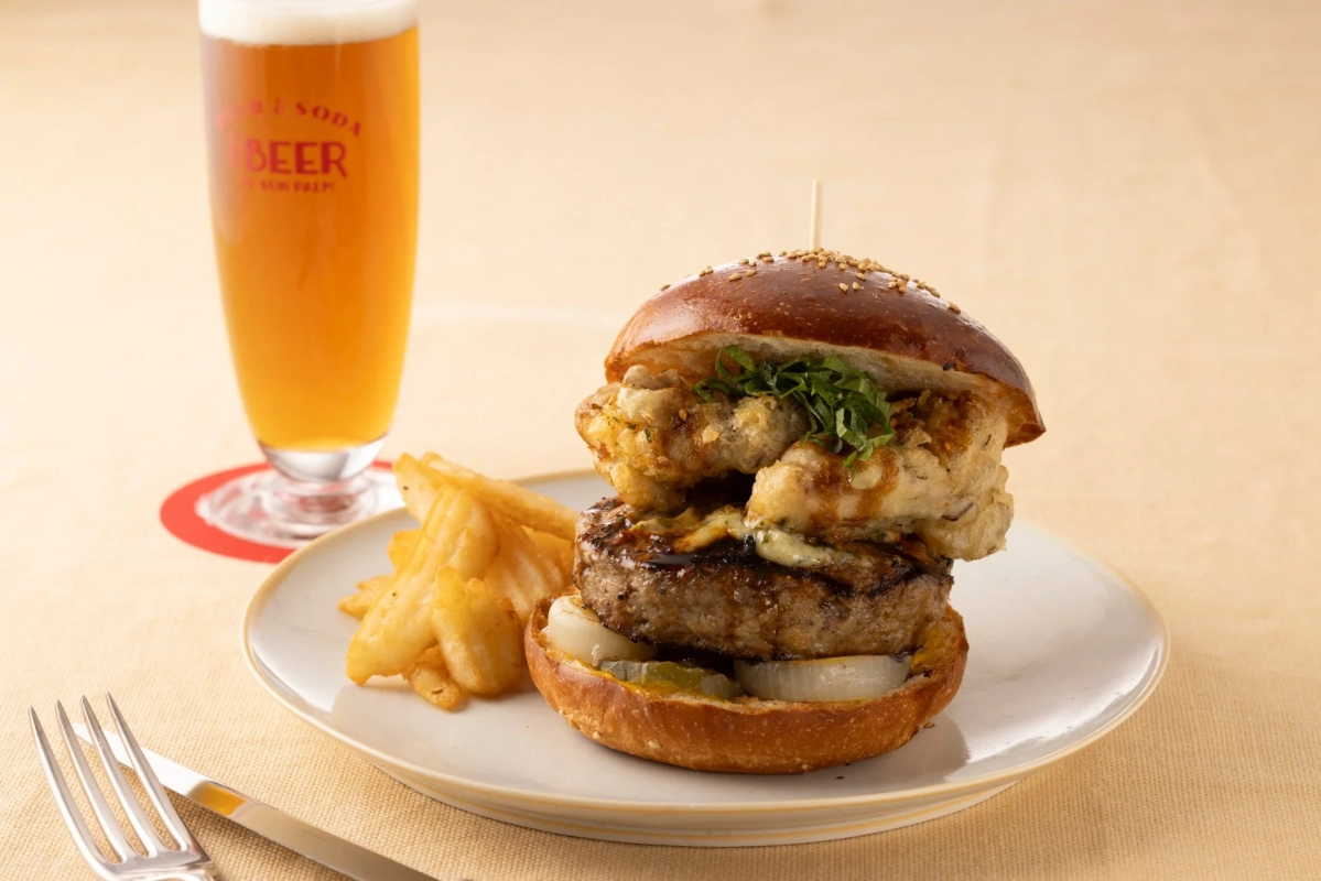 厚切りパティと揚げ物が特徴的なグルメバーガー、フライドポテト、ビールが盛り付けられたセット
