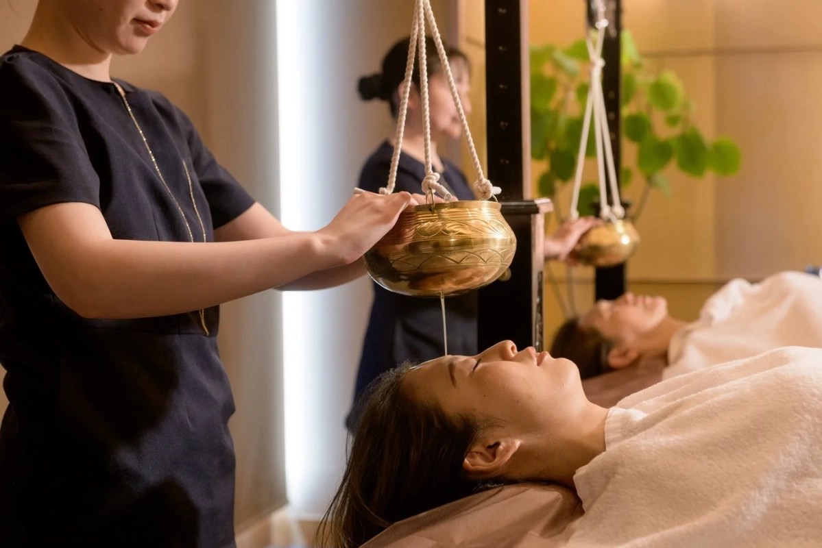 スパで女性がアーユルヴェーダのシロダーラ施術を受けている様子