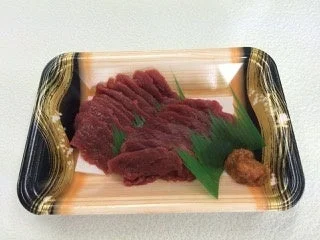 プラスチックトレーに薄切りの赤身肉が盛り付けられた馬刺し