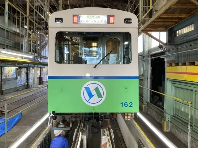 緑と白の電車が車両基地で整備を受けている様子