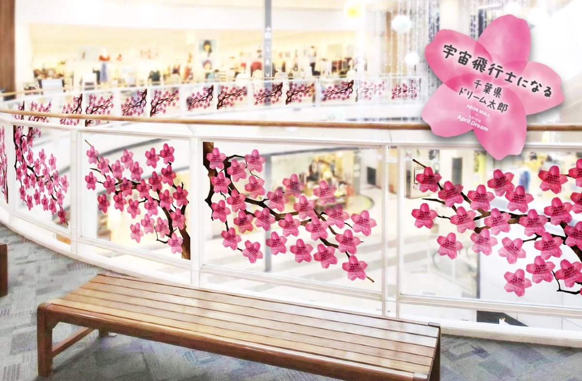 ショッピングモール内の手すりに、桜の形をしたピンクのメッセージカードが飾られています。大きなカードには「宇宙飛行士になる」という夢と「AEON MALL April Dream」とあり、多くの小さなカードにも願い事が書かれています。