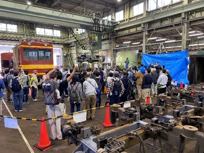 鉄道車両の整備工場で、多くの見学者が集まっている様子