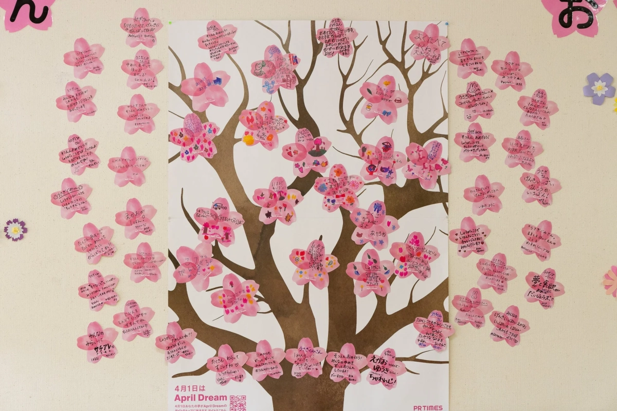 桜の木のポスターに、子供たちへの応援メッセージや夢を綴った桜形のカードが多数貼られている。合格祝いや新生活への激励、健康や笑顔を願う言葉が多く見られ、「April Dream」というイベントの一環として夢を共有する温かい雰囲気が伝わる。
