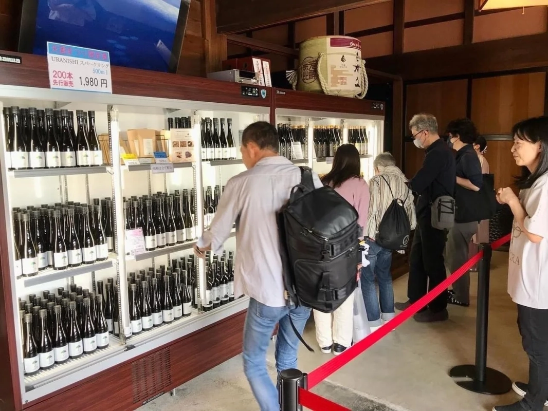 酒蔵のような店内で日本酒のボトルを見る人々