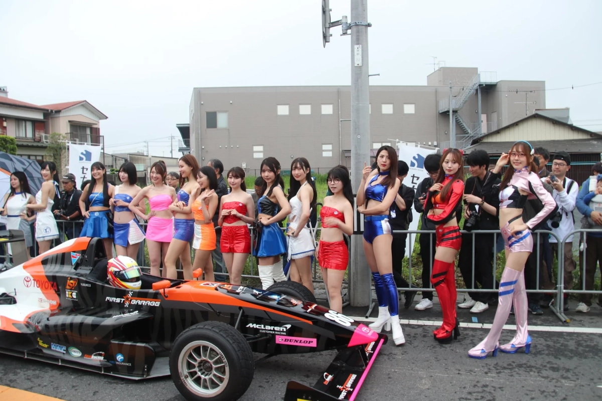 カラフルな衣装の女性たちとレーシングカー