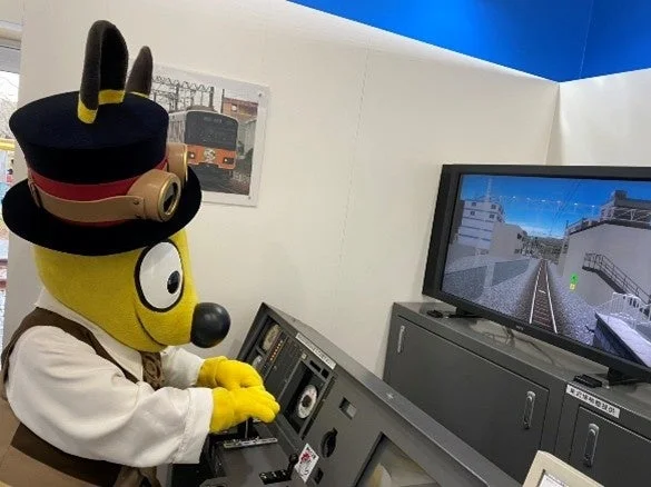 運転シミュレーターを操作するマスコット