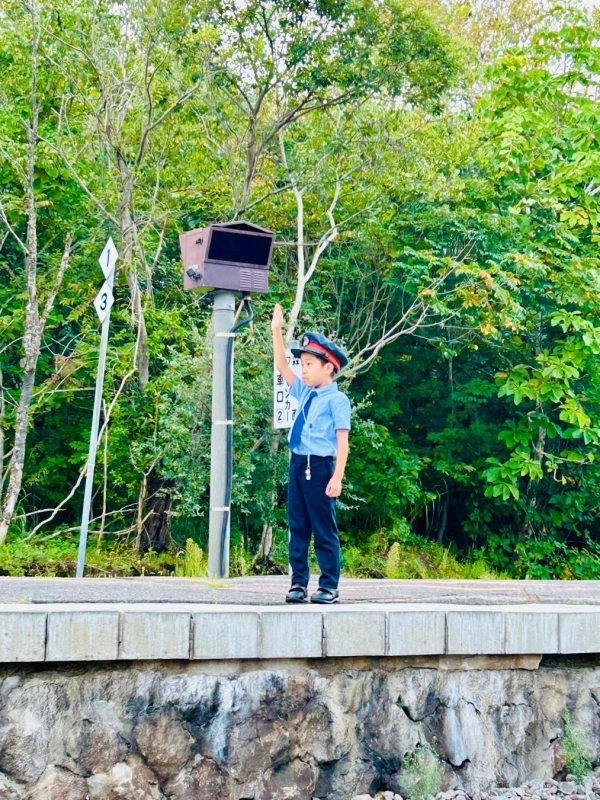 鉄道員の制服を着て指差喚呼をする子供