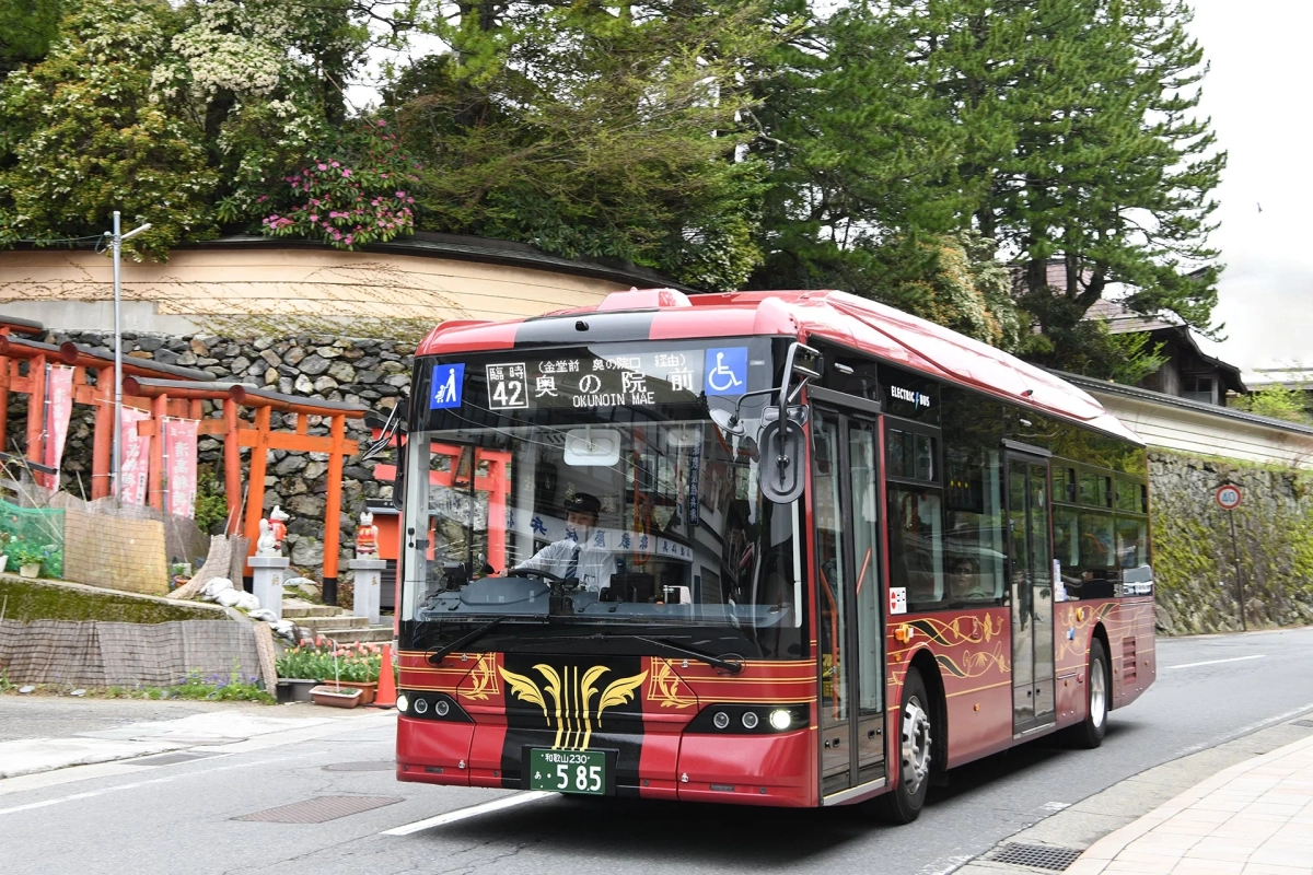 赤い電気バスが日本の山道を走っている様子