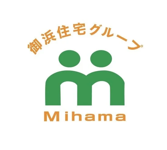 御浜住宅グループのロゴマーク。緑色の二つの人型が並び、アルファベットの「M」を象徴するデザイン。下部には「Mihama」の文字が配されており、住宅関連企業のシンボルを表している。