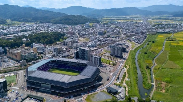 山々に囲まれた亀岡市のスタジアムと街並みの空撮