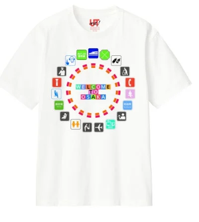 白いTシャツの中央に「WELCOME TO OSAKA」の文字がカラフルなブロックで描かれ、その周りを交通機関や公共施設、案内などを示す様々なピクトグラムが円状に配置されています。大阪への歓迎と観光案内をテーマにしたユニークなデザインです。