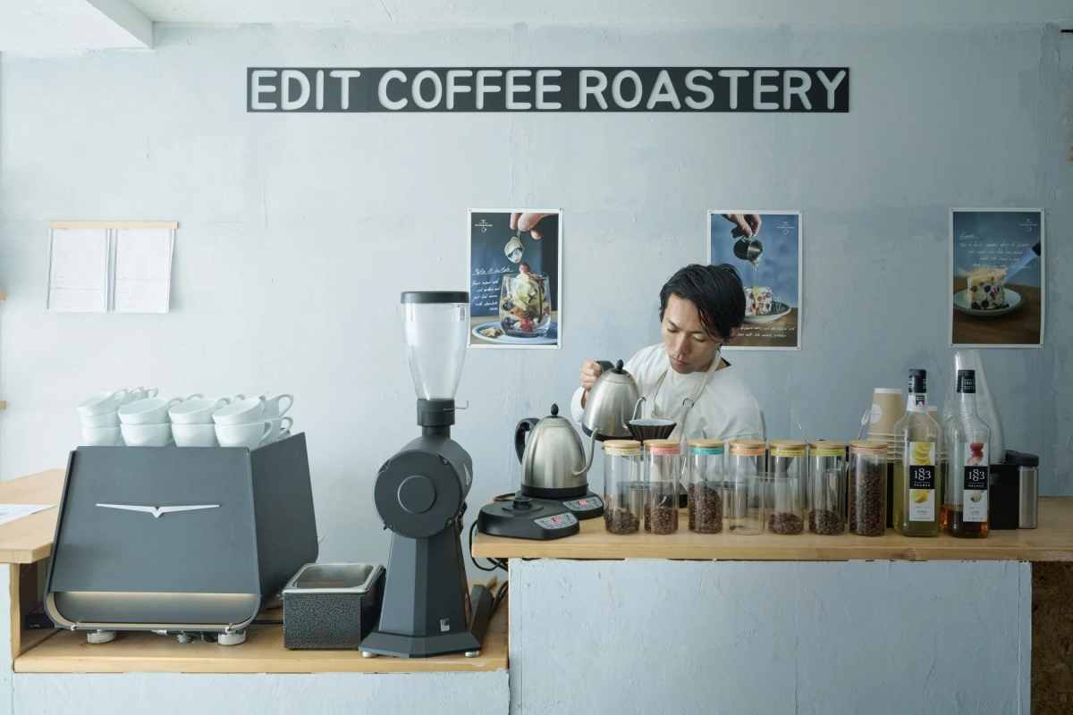 モダンな雰囲気のコーヒー焙煎所で、バリスタが丁寧にドリップコーヒーを淹れている様子