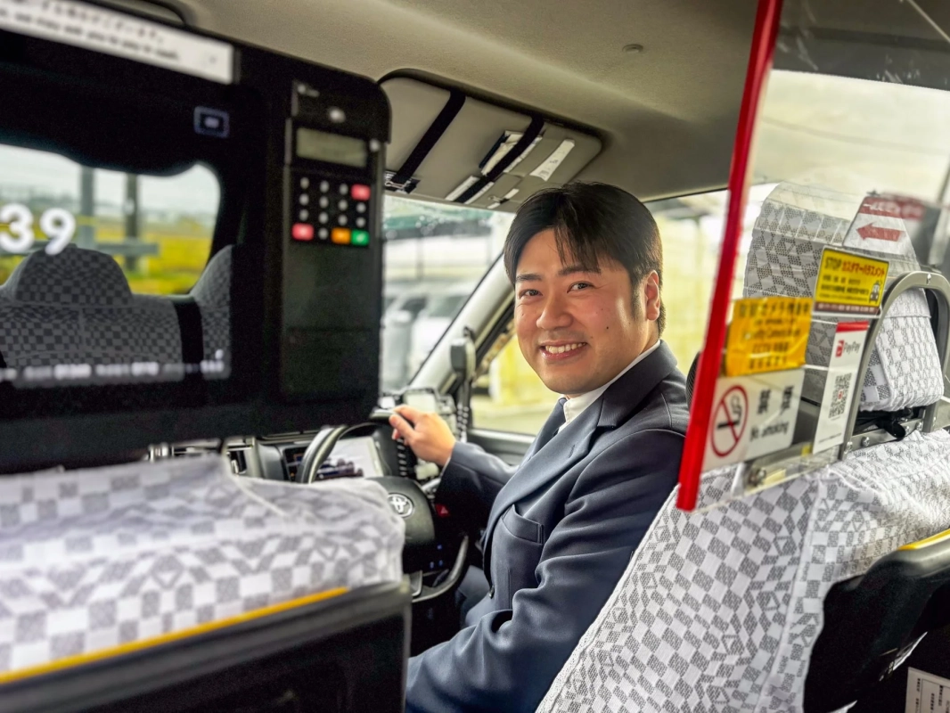 笑顔のタクシー運転手が車内で業務を行う様子