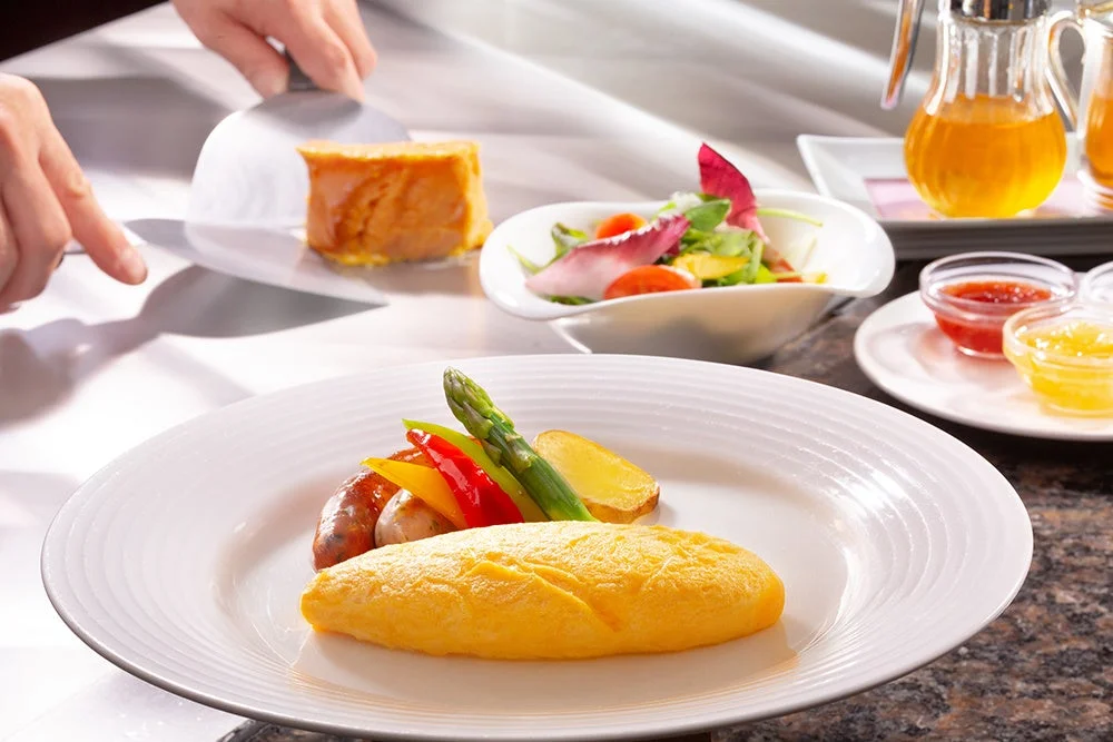 オムレツやソーセージなどが盛り付けられた洋食の朝食風景