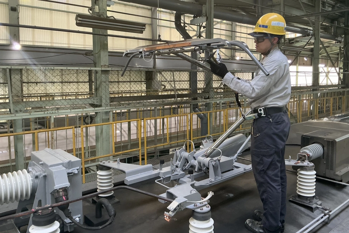 工場内で鉄道車両のパンタグラフを点検する作業員