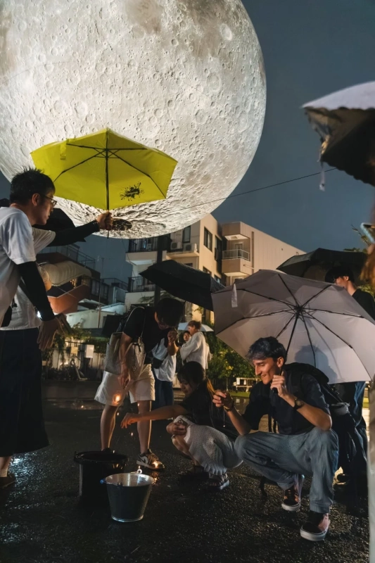 夜空の月と花火を楽しむ人々
