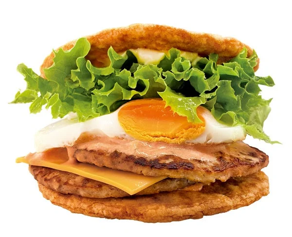 レタス、目玉焼き、ソース、2枚のパティ、チーズが挟まれたライスバンズのハンバーガー