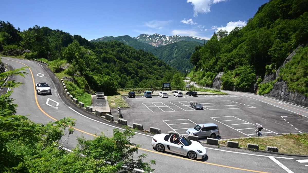 新緑の山道を走るオープンカー