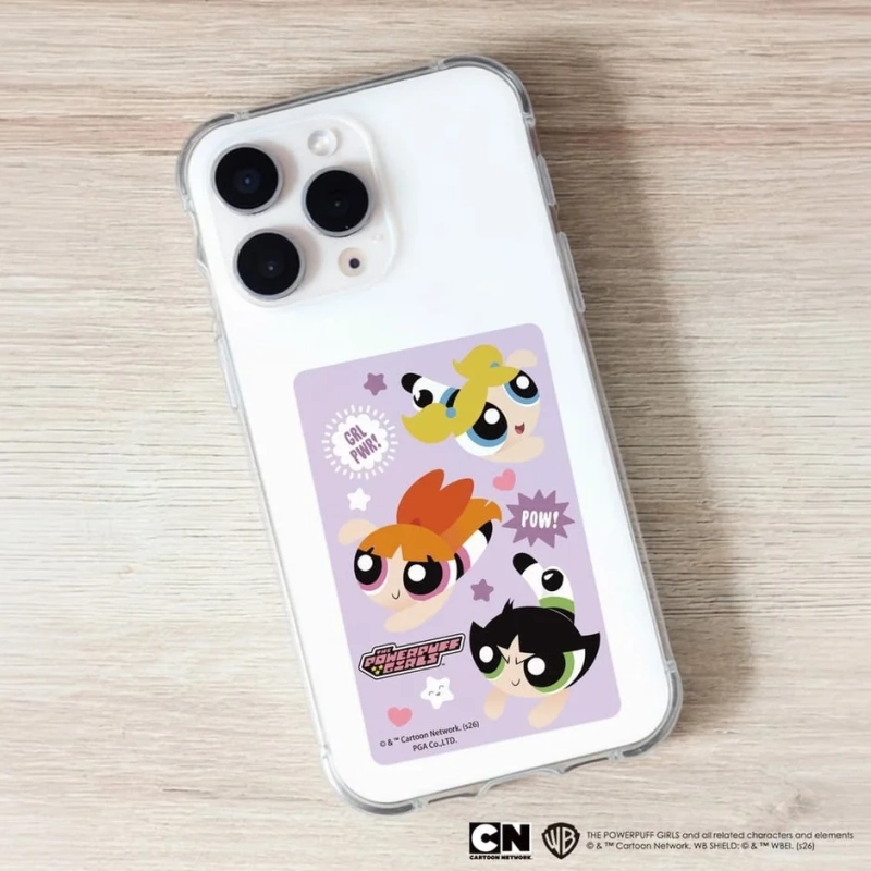 iPhoneのクリアケースに、パワーパフガールズのキャラクターがデザインされた紫色のステッカーが挿入されています。ステッカーには、ブロッサム、バブルス、バターカップが可愛らしく描かれ、「GRL PWR!」や「POW!」といった文字も配置されています。ポップで可愛らしいスマホアクセサリーです。