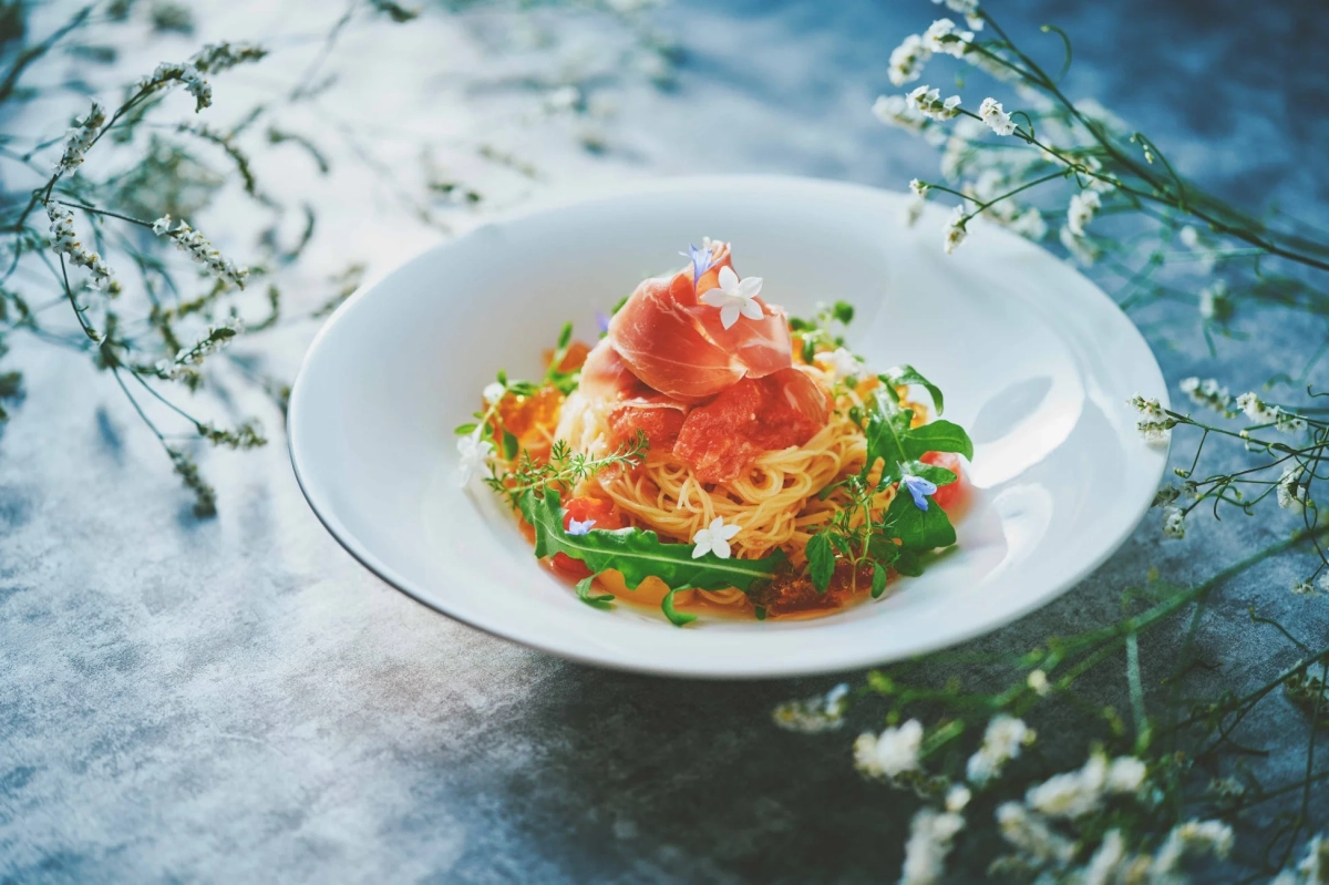 冷製パスタに生ハム、エディブルフラワーが添えられた一皿