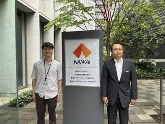 南海株式会社の看板の前で立つ男性たち