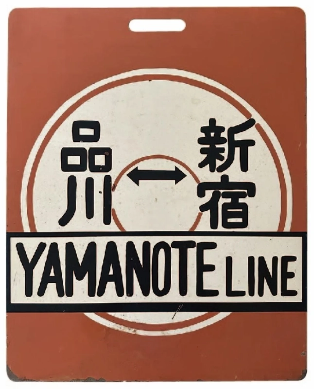 山手線の駅名である品川と新宿が両方向矢印で示され、「YAMANOTE LINE」と英語で書かれたレトロな案内板