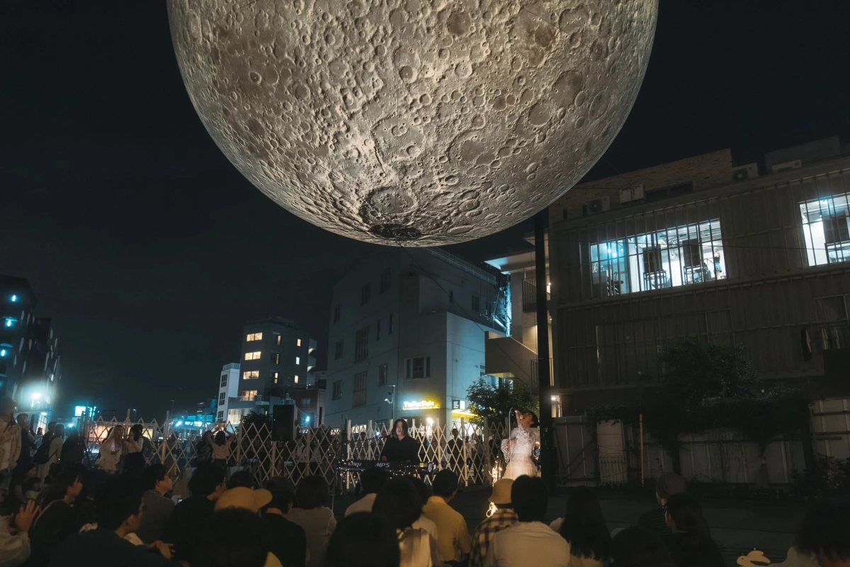 巨大な月のインスタレーションの下で行われる野外ライブ