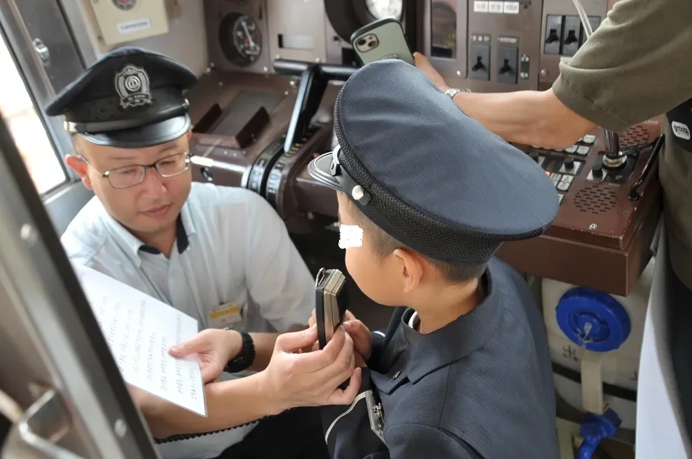 電車の運転席で運転体験をする子供と指導員
