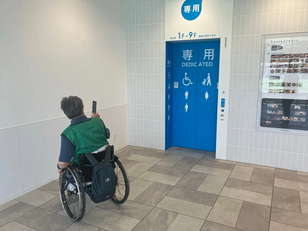 車椅子利用者がエレベーター案内を見ている様子