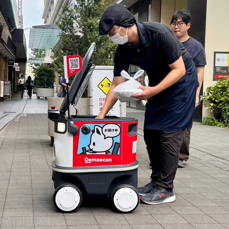 出前館の配達員が自動配送ロボットに商品を積み込んでいる様子
