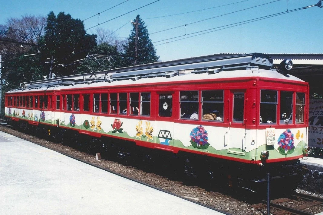 花柄の装飾が施された赤い電車が駅のホームに停車している様子