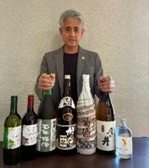 様々な種類のアルコールボトルを前に、両手でボトルを支える男性