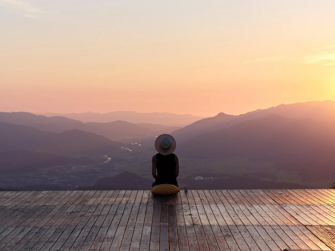 夕日に染まる山々を眺める人物