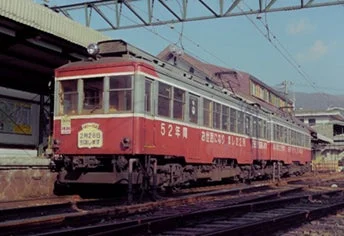 赤い旧型電車が駅のホームに停車している様子