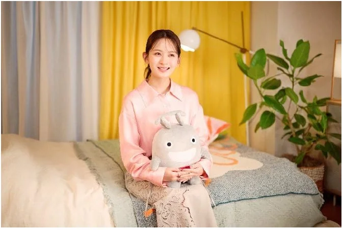 ベッドに座りぬいぐるみと笑顔の畑芽育さん