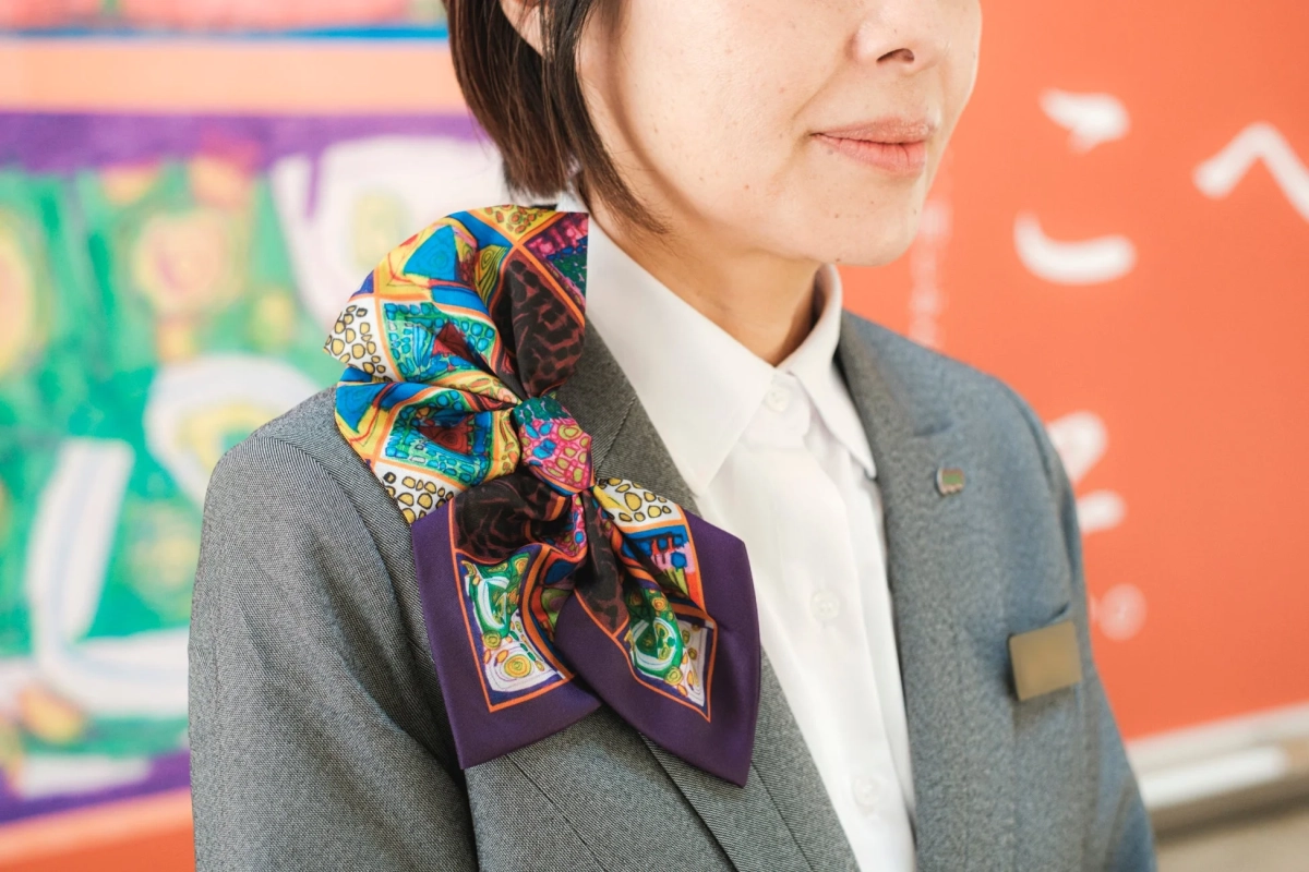 作品をあしらったスカーフを着用した女性スタッフ