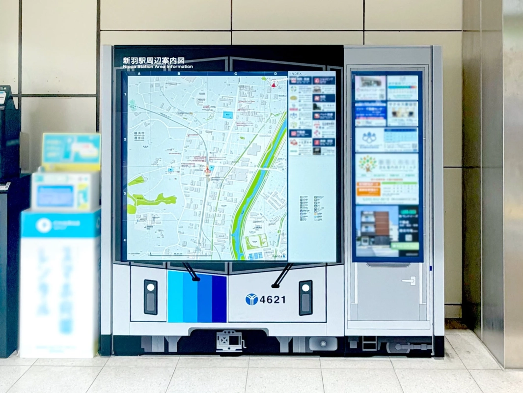 新羽駅の周辺案内図と情報が表示されたデジタルサイネージ。電車の先頭車両を模したユニークなデザインで、駅構内の情報提供に役立っています。