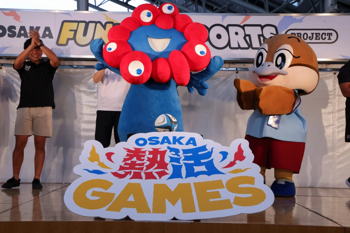 イベントステージで拍手する男性と2体のマスコット