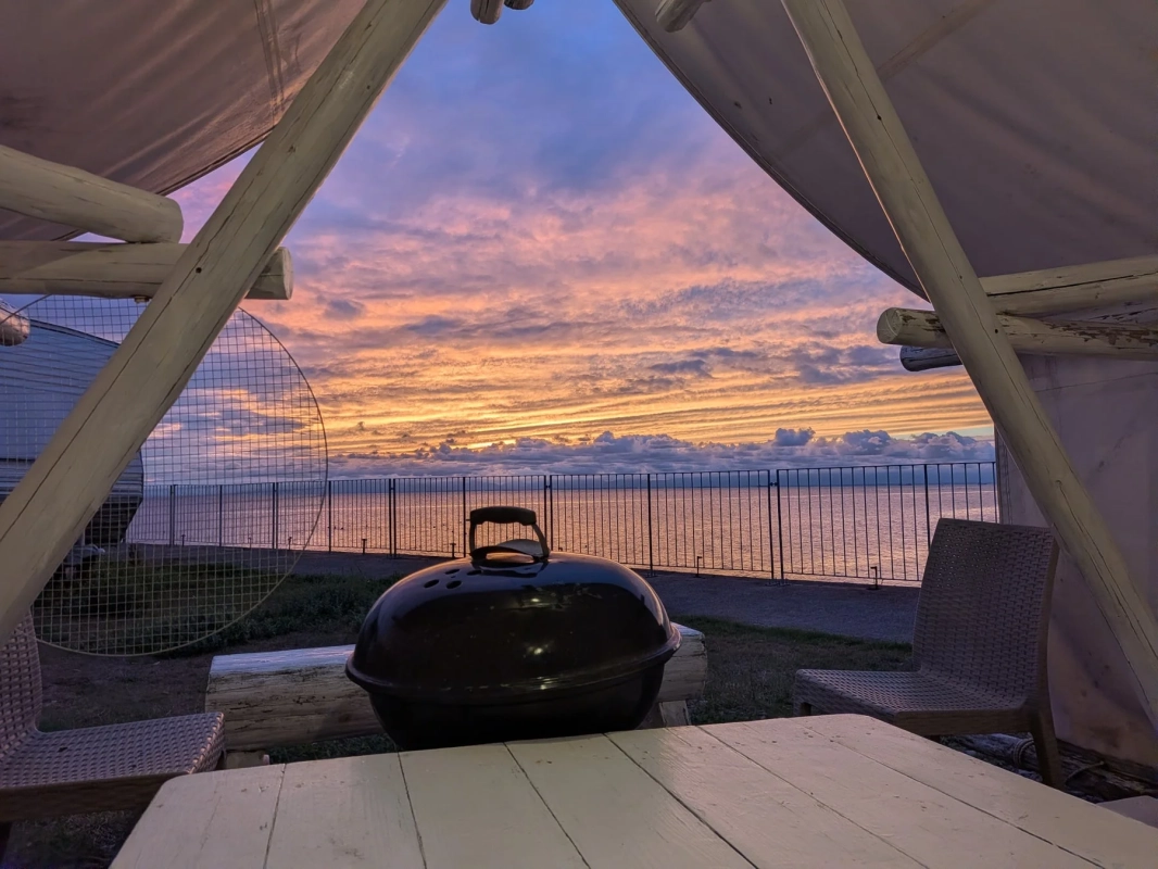 夕焼け空と海を望むテントの中からバーベキューグリル